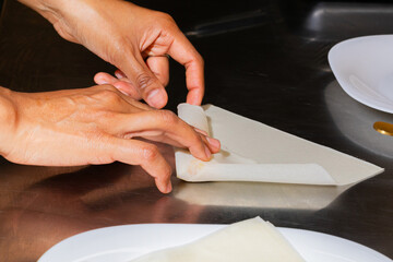 Hands craft delicate pastry triangles, echoes of Lunar New Year feasting, culinary dance of nimble...