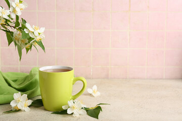 Cup of hot jasmine tea with flowers on white table