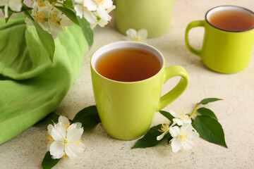 Cups of hot jasmine tea with flowers on white background, closeup