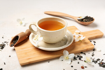 Cup of hot jasmine tea with flowers and dry leaves on white background, closeup