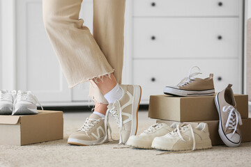 Young woman choosing new light sneakers at home