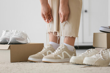 Young woman choosing new light sneakers at home