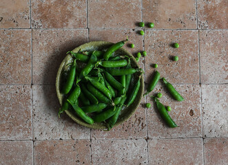 Fresh green peas in a ceramic plate on a stone background