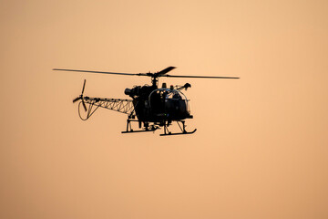 Silhouette Helicopter is flying against isolated mid-air on evening sky