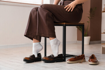 Young woman trying on new brown shoes in boutique