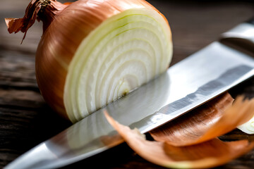 A sharp stainless steel knife slicing through a fresh halved yellow onion on a rustic wooden surface