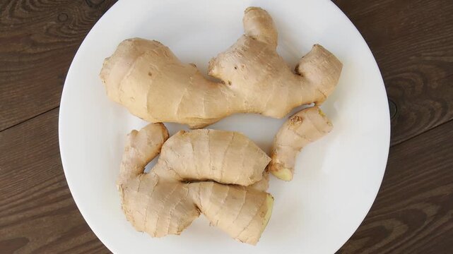 Fresh ginger root spinning gently on white ceramic plate, showcasing natural culinary ingredient with vibrant texture and pristine surface, highlighting fresh organic produce.