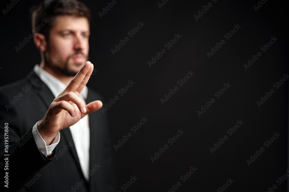 Poster man in suit making a gesture with hand against dark background during a focused moment of expression