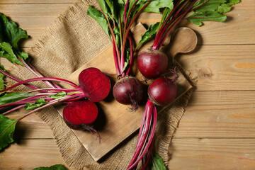 Board with fresh cut beetroots on wooden background