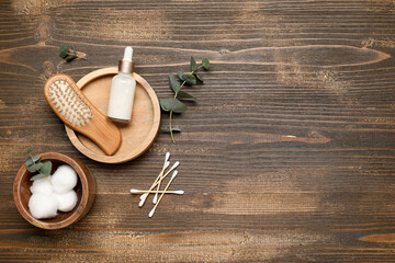 Composition with hair brush, cotton balls, swabs and bottle of cosmetic product on wooden background