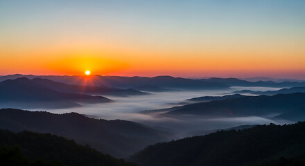 Obraz premium Dramatic sunrise over mountain range with layers of fog and clouds