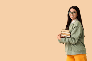 Beautiful woman with books on beige background
