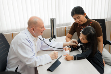 Obraz premium Caucasian Doctor use stethoscope take care Asia kid girl with assistant at hospital 