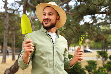 Male gardener with shovel and rake outdoors