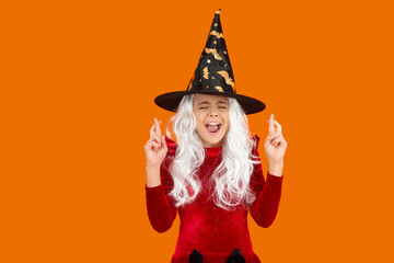 All Hallows witch. Girl making a wish in Halloween witch costume. Happy Halloween wish. Girl witch...