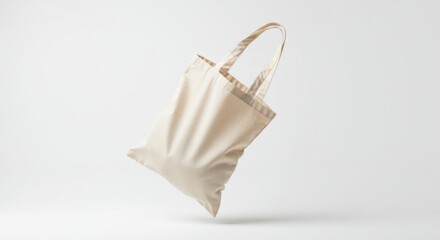 An off-white canvas tote bag captured mid-air, casting a soft shadow on a light gray surface