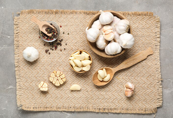 Wooden bowls with fresh garlics and peppercorns on grey background