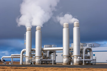 Steam billows from geothermal power plant under dramatic clouds in Iceland