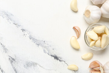 Glass bowl with fresh garlic cloves on white background