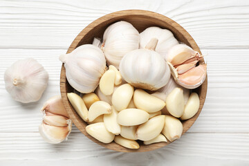 Bowl with fresh garlics on white wooden background
