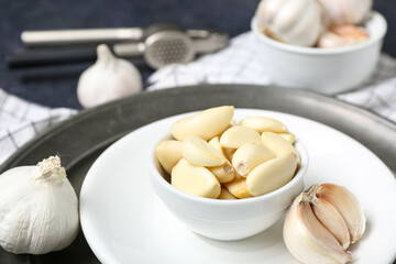 Bowl with fresh garlic cloves on dark background, closeup