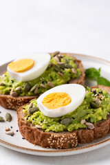 Avocado toast with boiled egg, sunflower seeds, pumpkin seeds and sesame seeds on plate, Healthy eating