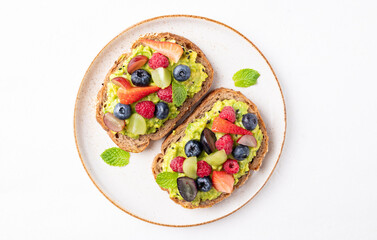 Top view of avocado toast with strawberry, blueberry, raspberry and grape. Healthy eating