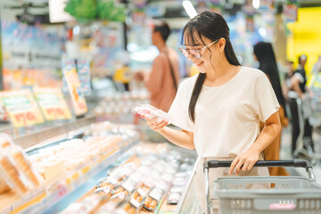 Young adult asian woman consumer choosing ready meals food at japanese supermarket store choice buying