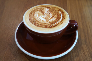 Close up red ceramic mug cup of hot Latte art coffee on wooden table