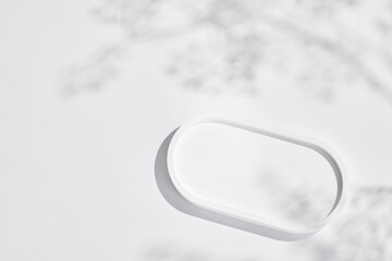 empty isolated white clean simple plaster tray and oval ceramic base stand with tree shadow and shade silhouette on desktop tabletop display background
