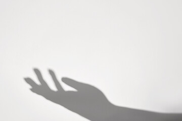 isolated person palm hand gesture gray shadow and arm silhouette black shade on white wall background