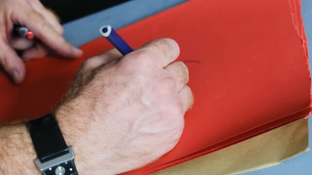 Man draws mannequin with felt tip pen on coloured sheet of paper. Student draws silhouette and applies contour drawing techniques creating outlines