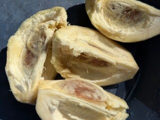 Close up highlights inside fresh jackfruit segments revealing pulp and seeds on dark surface
