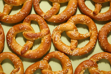 Many tasty salted pretzels on green background