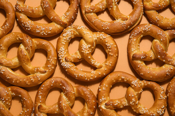 Many tasty salted pretzels on brown background