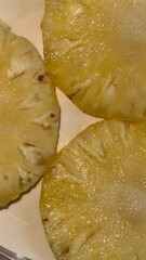 Close up shows the glistening golden yellow pineapple fruit slices on a plate