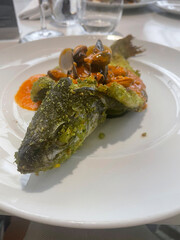 Whole baked fish crusted with herbs, topped with a rich tomato seafood sauce with mussels and clams.