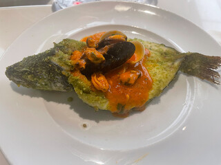 Whole baked fish crusted with herbs, topped with a rich tomato seafood sauce with mussels and clams.