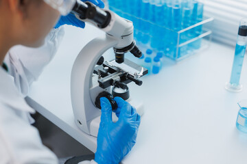 Scientist using microscope doing research in laboratory