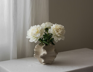 Bouquet of white peonies in a creative ceramic vase on the table
