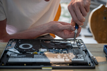 Man repairing laptop with tools on table, computer maintenance concept