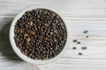 Green coffee beans in a bowl on a white wooden table. Alternative drink concept. Selective focus. Horizontal orientation. Top view. Copy space