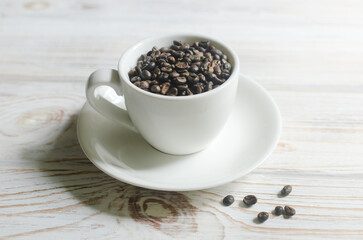Green coffee beans in a small white coffee cup on the wooden table. Alternative drink concept. Selective focus. Horizontal orientation.