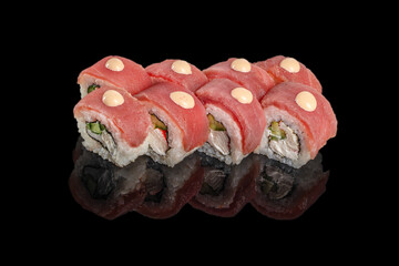 Tuna-topped sushi rolls with creamy sauce dots and fresh vegetable filling presented on a sleek black reflective surface