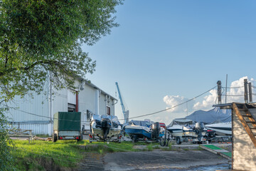 Obraz premium Boats on the shore near the slipway with a small crane for launching into the water. Preparing boats for the deep blue water glimpse into maritime craftsmanship.