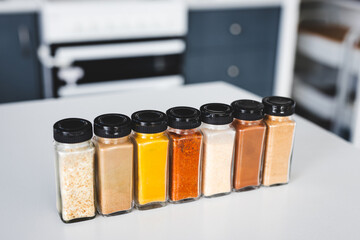 organised tidy spice jars on kitchen countertop featuring pantry staples and different flavours for...