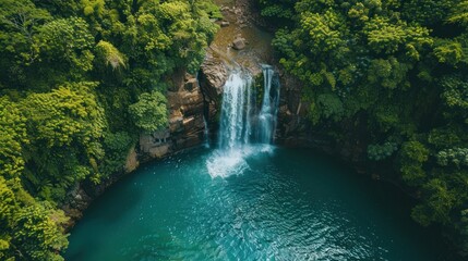 Majestic Waterfall Plunging into Turquoise Pool, Surrounded by Lush Greenery, Aerial View