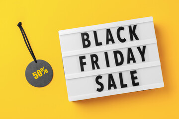 Black friday sale word on lightbox with sale tag on yellow background