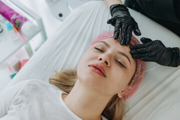 young woman getting professional face massage at aesthetic clinic