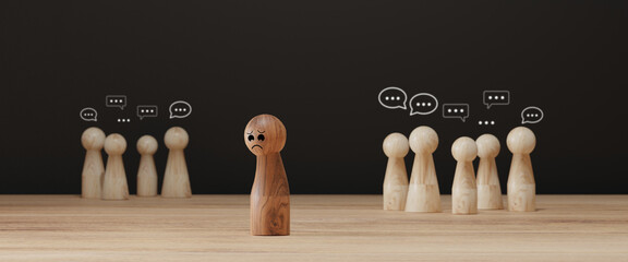 Sad wooden figure excluded from group. Concept of bullying, discrimination, isolation, loneliness,...